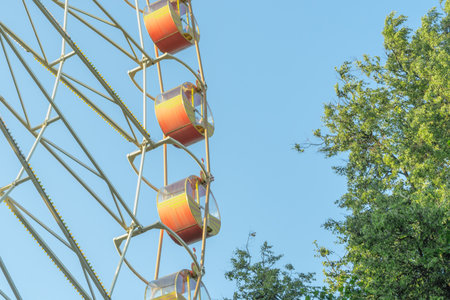 Ferris Wheel And Green Trees Against Blue Sky. Summer Amusement Park Scene With Ferris Wheel Rising...