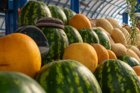 Watermelons and melons stacked at market stall with digital scale. Fresh watermelons and melons...