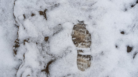 Footprint on fresh snow revealing ground texture. First step on untouched snow symbolizing solitude journey and human presence in nature.の写真素材