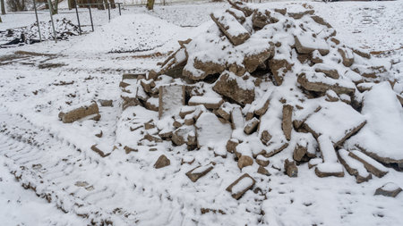 Snow covered concrete debris at demolition site. Winter demolition scene with broken concrete slabs...