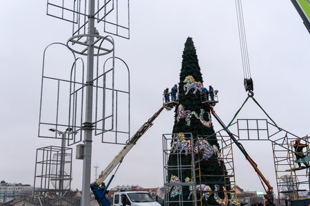 Workers assembling a large artificial christmas tree in urban square. Urban holiday preparations...
