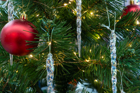 Red Christmas ornament hanging on pine tree branch. Festive red bauble nestled among green pine needles in natural outdoor winter setting.の写真素材