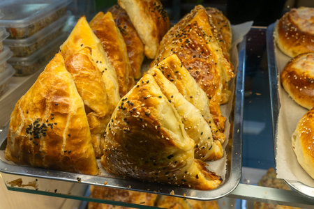 Golden uzbek samsa pastries. Freshly baked triangular samosas with black and white sesame seeds on...