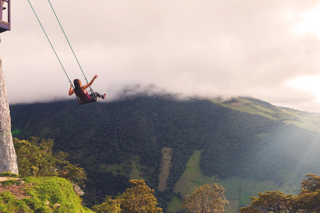 Silhouette Of An Young Happy Woman On A Swing, Swinging Over The Andes Mountains, Tree House, Ecuadorの写真素材