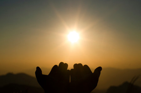 Human's hands pray on blurred light background , soft focusedの写真素材
