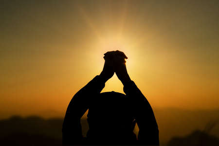 Man praying, meditating in harmony and peace at sunset. Religion, spirituality, prayer, peace.の写真素材