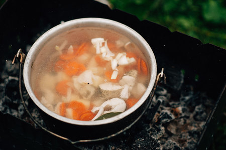 The process of cooking in the campaign. Metal bucket of fish soup on the fire. fish soup, bonfire, fishing pikeの写真素材