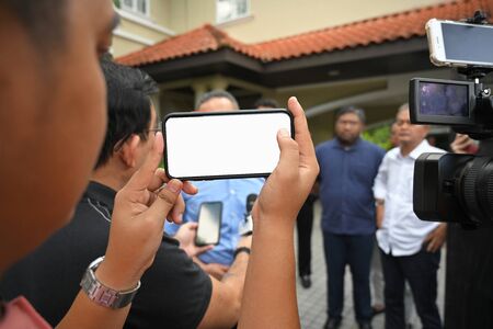 Man holding smart phone on interview with blurred background. For Graphic display montage.