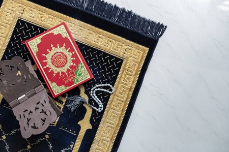 Muslim Holy Quran and rosary or tasbih with praying mat rug or sejadah isolated white