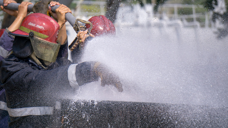 Fire fighters are extinguishing huge fire with waterの写真素材