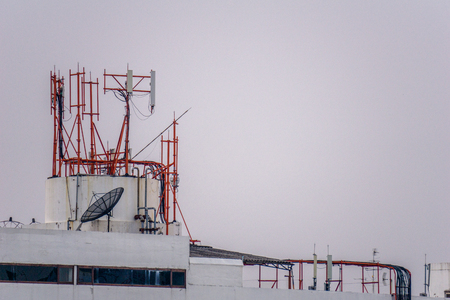 Group of communication posts with so many frequency radio antennas and TV satellite dish on the roof top of the tall building.の写真素材