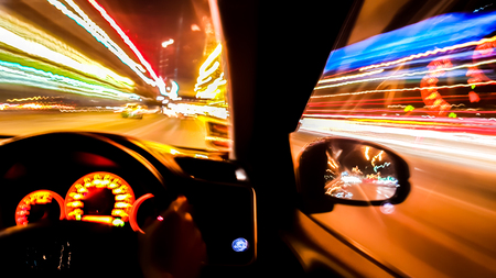 Light trial of the night road including light from car's console and side mirror taken when the car is moving with blurring technic.の写真素材