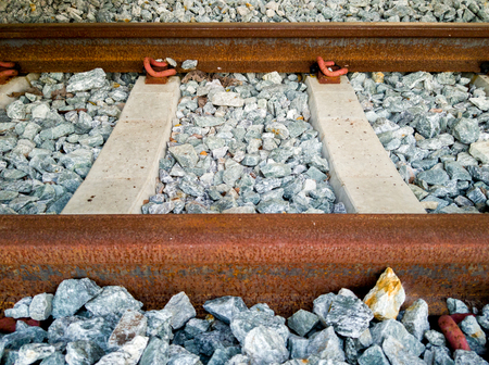 Inactive railroad covered with red rust lay down on the concrete sleepers and rocks foundationの写真素材