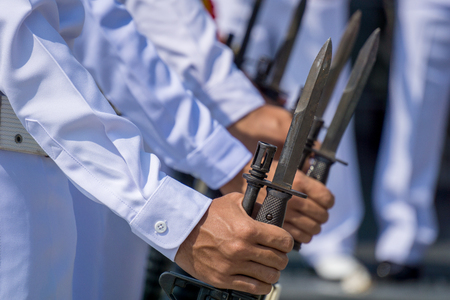 Navy officer in summer white uniform hold M16 rifle with bayonet preparing for salute VIP.