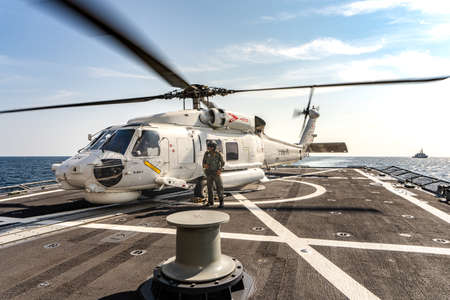 PHUKET, THAILAND - APRIL 9, 2019:  PHUKET, THAILAND - APRIL 9, 2019:  Sikorsky MH-60S Seahawk helicopter lands on the flight deck of the HTMS. Bhumibol Adulyadej stealth frigate of Royal Thai navy with air operator prepare for take off