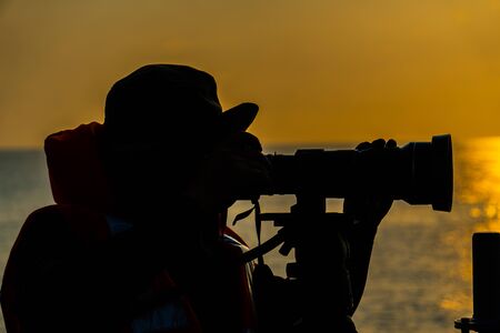 silhouette portrait of the man who shoot photography in the sea.