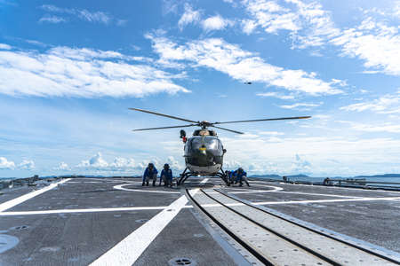 CHONBURI, THAILAND - JULY 9, 2020:  Seamen chalk and chain an Eurocopter EC 645 T2  helicopter on the flight deck aboard the guided-missile stealth frigate HTMS. Bhumibol Adulyadej.のeditorial素材
