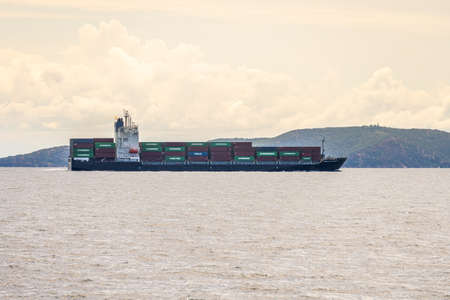 CHONBURI, THAILAND - JULY 9, 2020: Container ship with full load of containers sail in the shore...