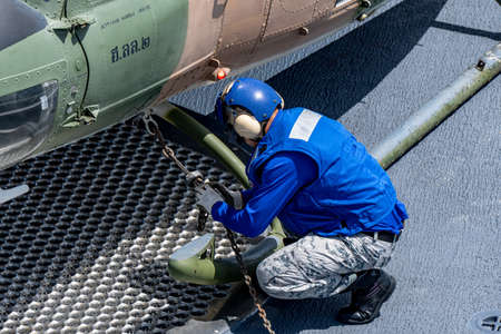 CHONBURI, THAILAND - JULY 9, 2020: Ship's crew ties down the Bell 212 helicopter of royal Thai navy...