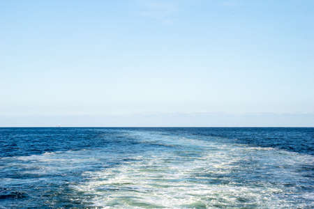 Wake of water created by ship that sailing through the calm sea water.