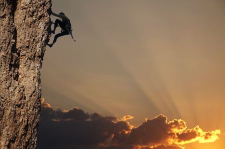 Climber silhouette on the rock on sunsetの写真素材