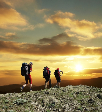 Group going along hill on sunsetの写真素材