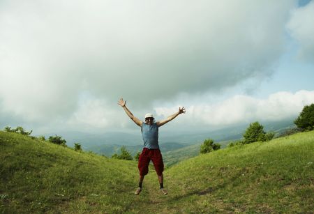 Jumping man on green hillsの写真素材