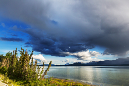 Serene scene by the mountain lake in Canada with reflection of the rocks in the calm water.の写真素材