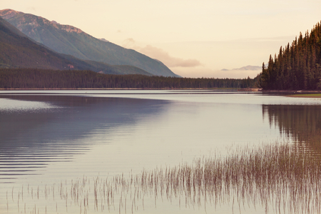 Serene scene by the mountain lake in Canada with reflection of the rocks in the calm water.の写真素材