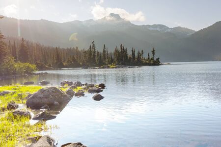 Serene scene by the mountain lake in Canada with reflection of the rocks in the calm water.の写真素材