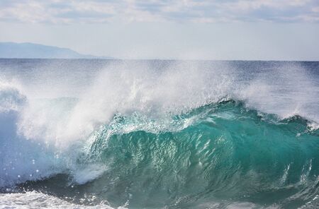 Blue wave on the beach. Blur background and sunlight spots. Peaceful natural background.