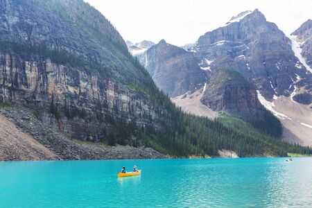 Beautiful turquoise waters of the Moraine lake with snow-covered peaks above it in Banff National...