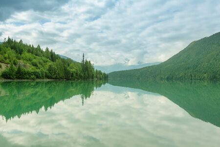 Serene scene by the mountain lake in Canada with reflection of the rocks in the calm water.