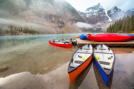Beautiful turquoise waters of the Moraine lake with snow-covered peaks above it in Banff National...