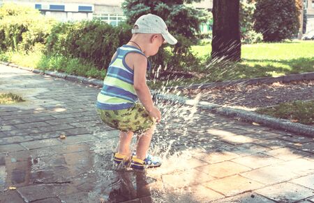 Little boy jumping in puddle. Summertime playgroundの写真素材