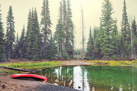 Red Canoe on green lake in forestの写真素材