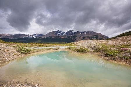 Serene scene by the mountain lake in Canada with reflection of the rocks in the calm water.の写真素材