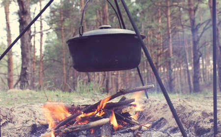 Touristic kettle on fire of burning campfire in camping in the hike. Cooking food in forest on...