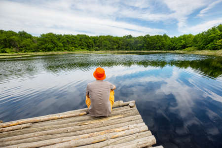 A man is resting at ease by the calm lake. Relaxation vacationの写真素材