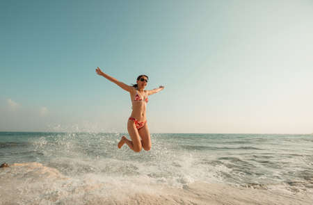 A young woman playing in the waves on a sea beachの写真素材