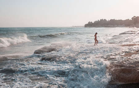 A young woman playing in the waves on a sea beachの写真素材