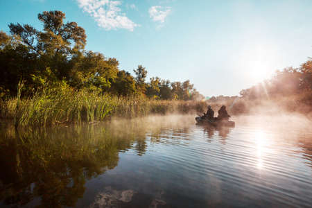 fishermen on a boat fishing on a river at dawn. Summer recreation.の写真素材