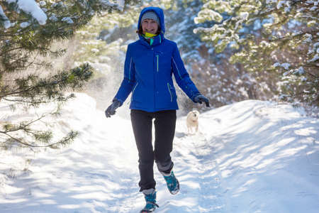 Young woman in  snowy forest  at sunny winter dayの写真素材