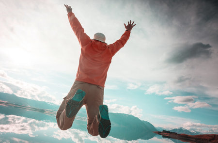 a man jumps off a cliff into a mountain lakeの写真素材
