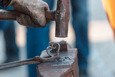 The blacksmith manually forging the molten metal on anvilの写真素材