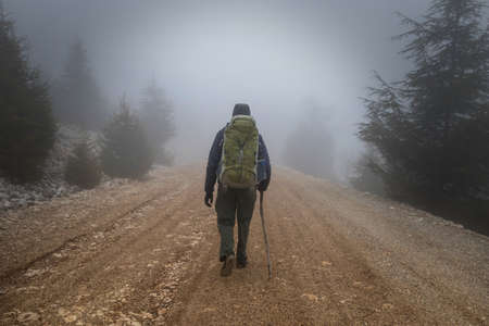 hiker walks along the road in the fogの写真素材