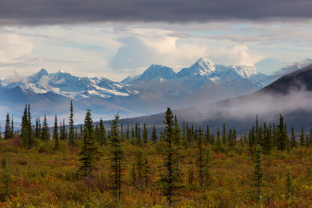 Picturesque Mountains of Alaska in autumn. Snow covered massifs, glaciers and rocky peaks, orange...
