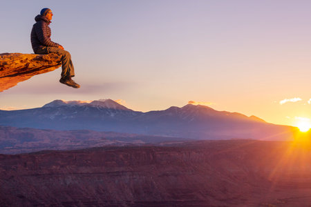 Man on the mountains cliff at sunrise. Hiking scene.の写真素材