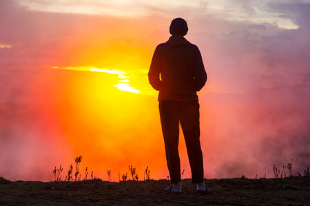 Happy man standing on a cliff at sunset.