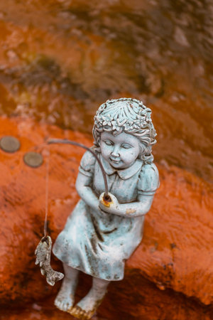 Small garden sculpture- fishing girlの写真素材